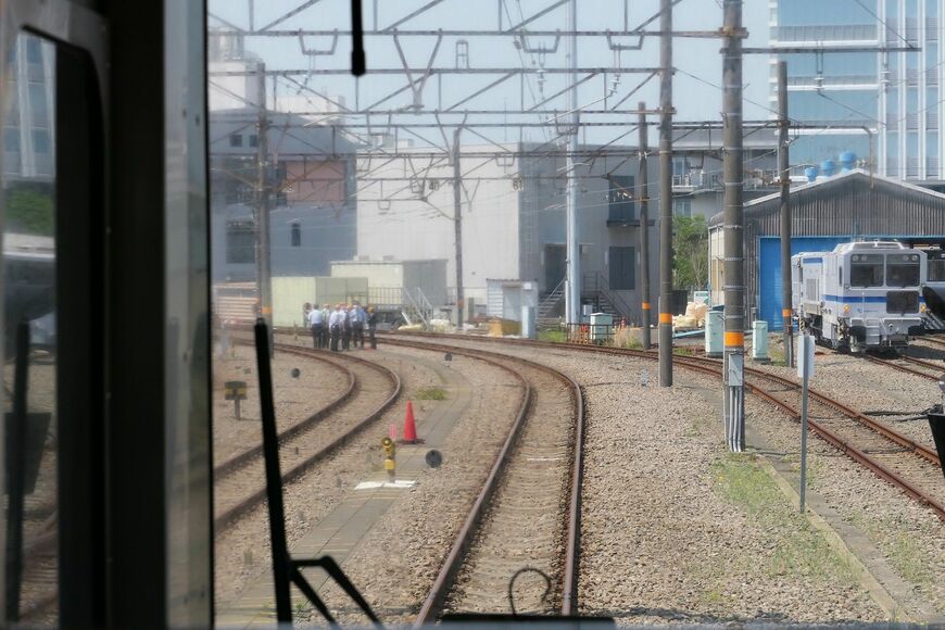 まず赤の三角コーンまで乗車して誘導。その後降車して線路脇から手旗で誘導する（記者撮影）