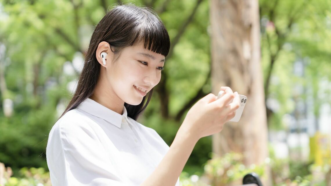 公園のベンチに座り、スマホで動画を観る少女