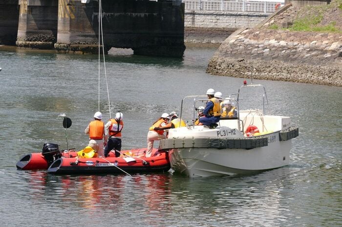 ボートから海上保安庁の救難艇に乗り移る