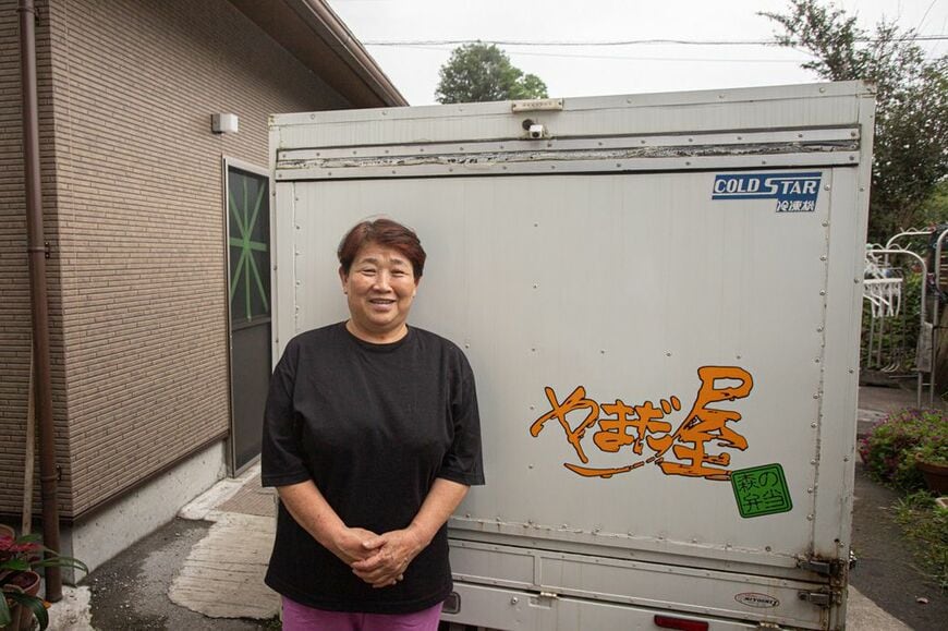 山田まゆみさん。配送用の車の前で（筆者撮影）