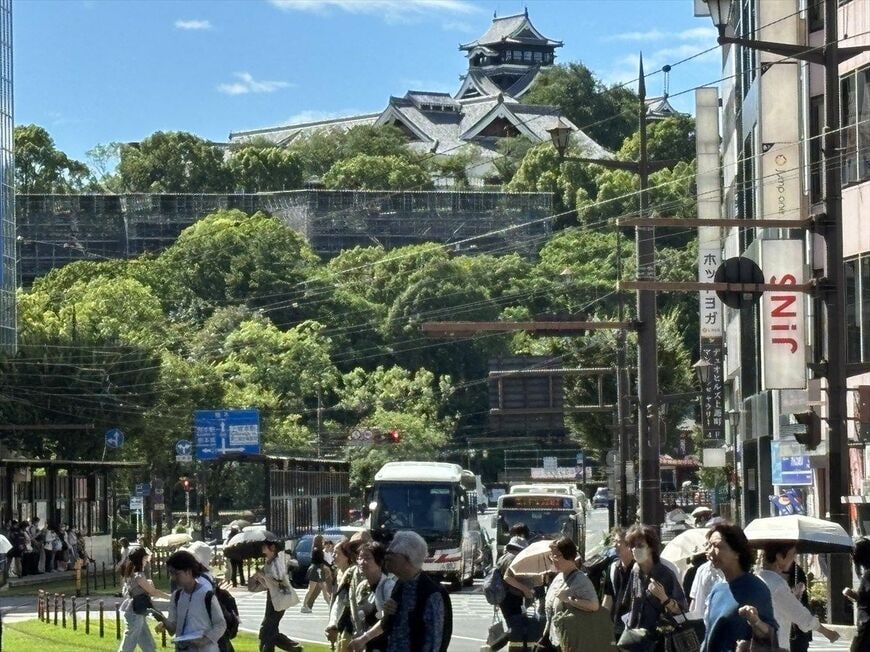 熊本城を背景に複数のバスが走る道路の様子（筆者撮影）
