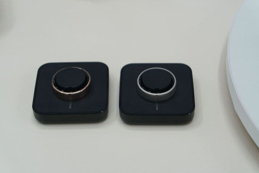 からだメイト Ringのゴールドとシルバー。専用充電台に載せて充電する（写真：筆者撮影）