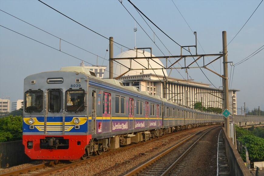 ジャカルタのアイコンでもあるイスティクラルモスクをバックに高架線を快走する、元東急8000系の8039編成（筆者撮影）