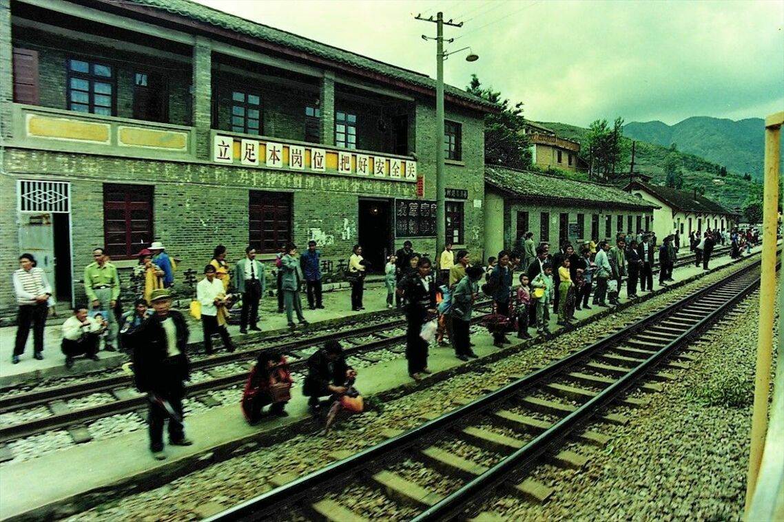 ホームのない駅で対向列車を待つ人々